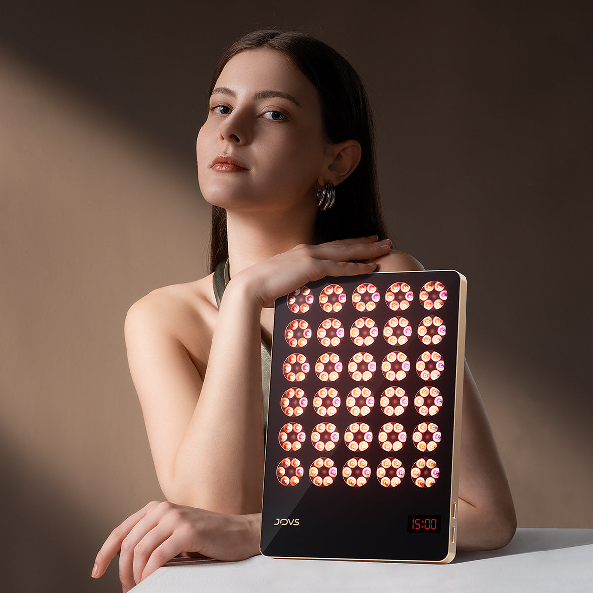 Woman using JOVS Alva LED Therapy Device for full-body skincare, highlighting portability and effectiveness.
